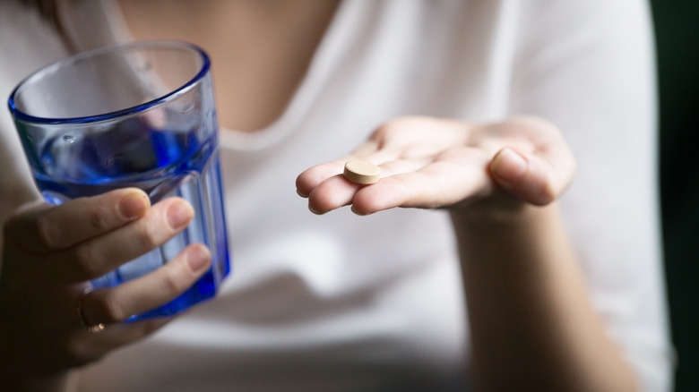 Woman holding pill and glass of water