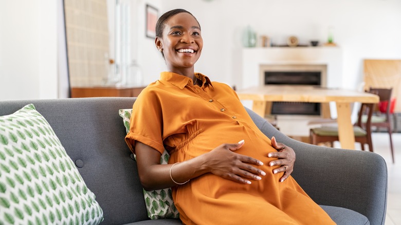 pregnant woman smiles holding belly