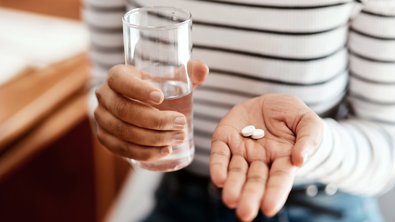 Hands holding pills and water