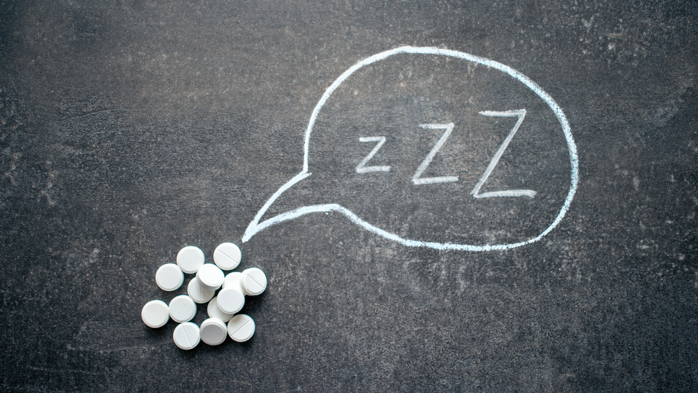 White pills on chalkboard with letters Zzz in a speech bubble