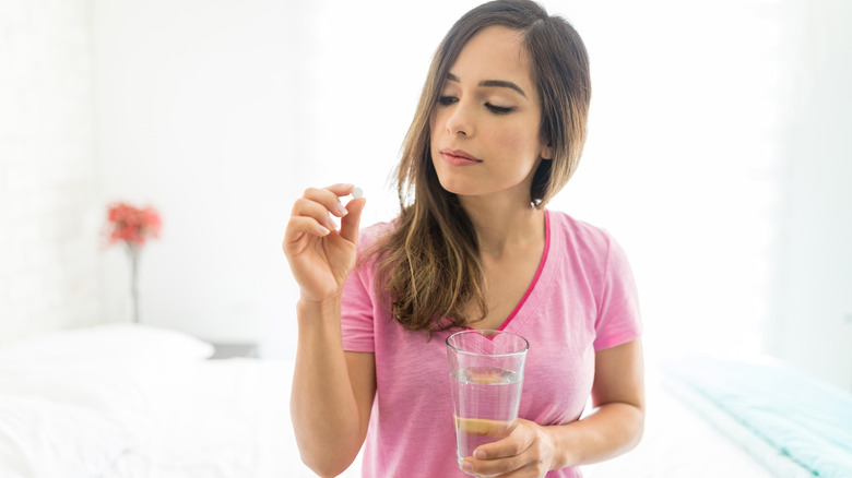 a woman holds emergency contraceptive and a glass of water 