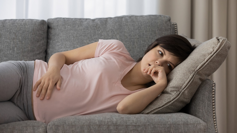 Pregnant woman lying on couch worried