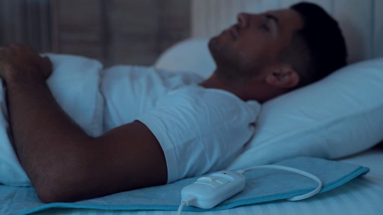 Man sleeping with heating pad on bed