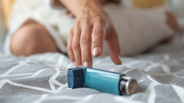 woman reaching for inhaler on bed