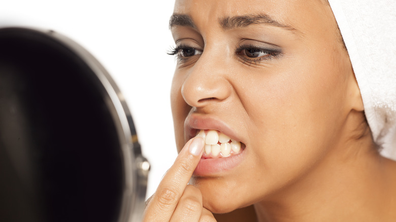 woman looking at her teeth in mirror