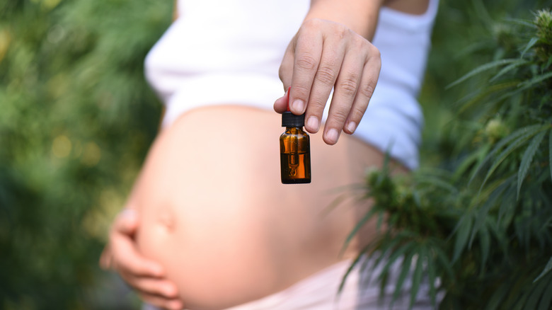 Pregnant woman holding bottle of CBD oil