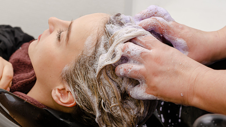 Stylist applying purple shampoo after dyeing