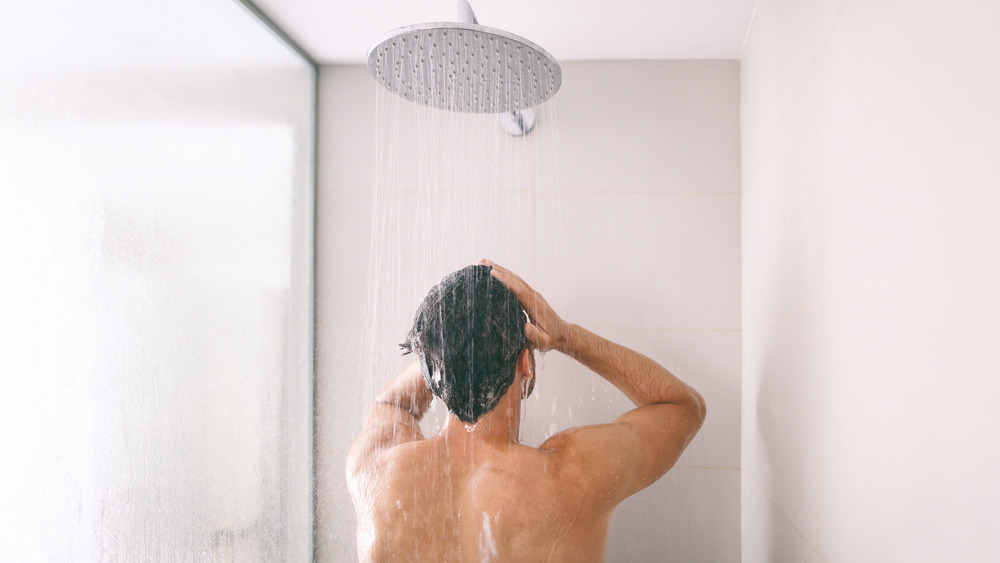 A man showering under a rainfall showerhead 