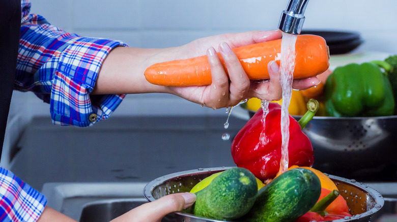 Hand rinsing a bowl of produce under running water