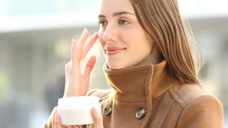 woman putting on retinol cream outside