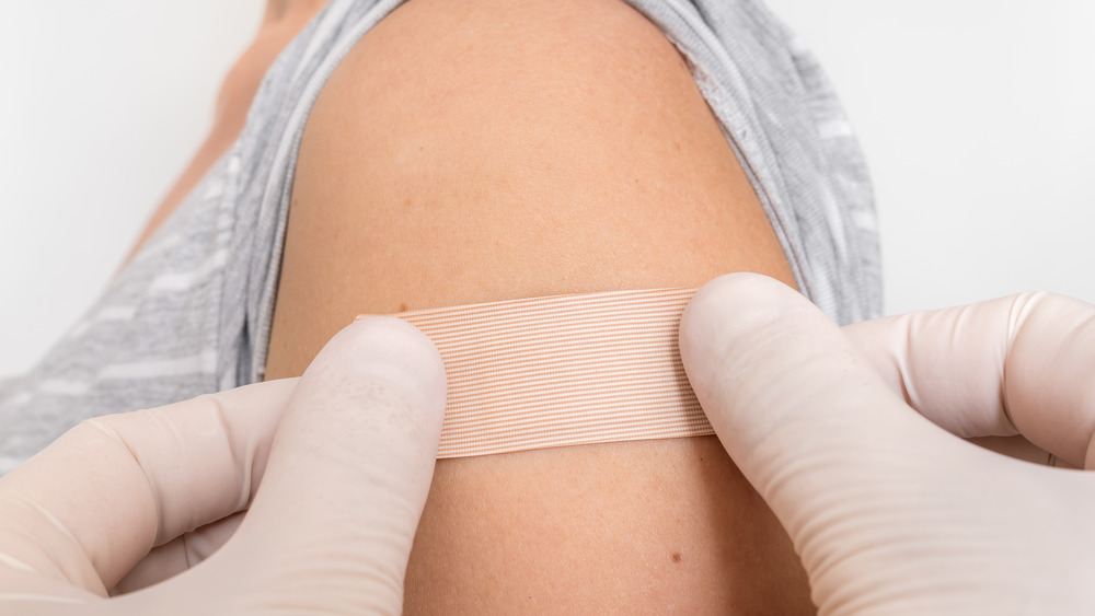 Person places a band-aid on a woman's upper arm 