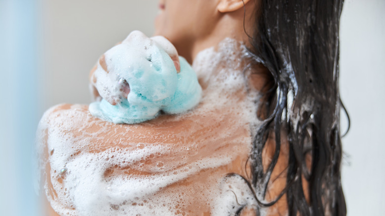 woman using loofah in shower