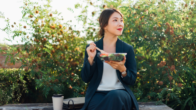 A woman sitting outside eating a healthy salad