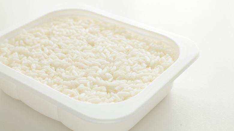 White plastic container of white rice on white background