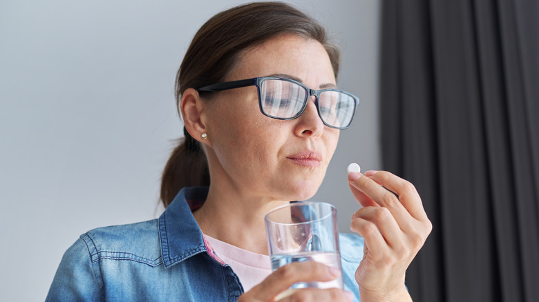 Woman holding pill and water