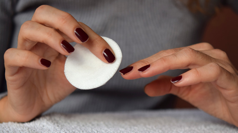 Woman's hands using nail polish remover