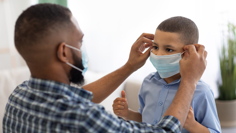 A father puts a face mask on his son