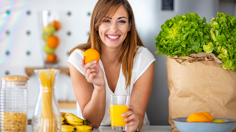 Woman holding a glass of orange juice and smiling