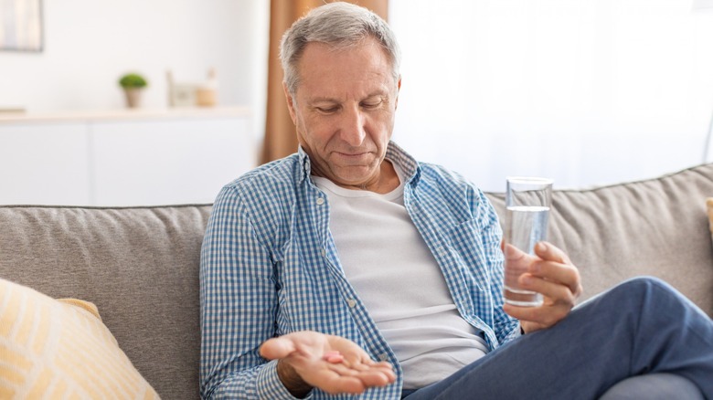 man hold Paxlovid tablets and glass of water