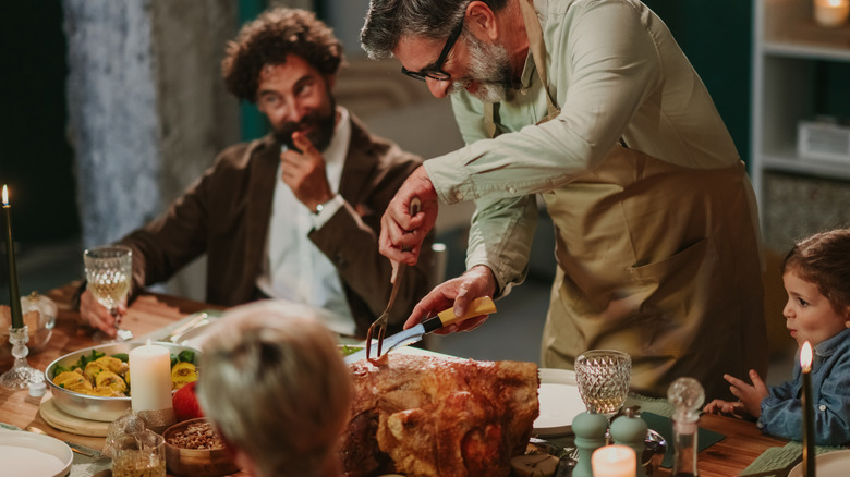 A man carving a turkey at a holiday dinner