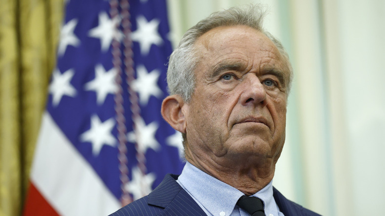 Robert Kennedy Jr. standing in front of a flag