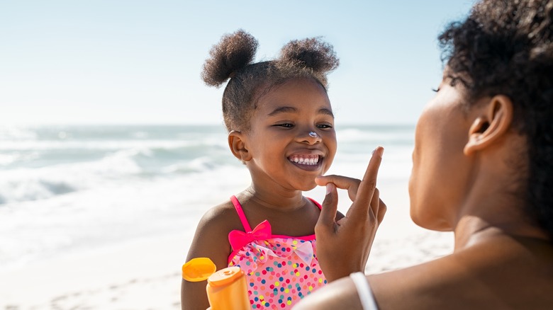 A mom puts sunscreen on her child