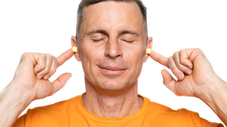 man inserting earplugs in ears