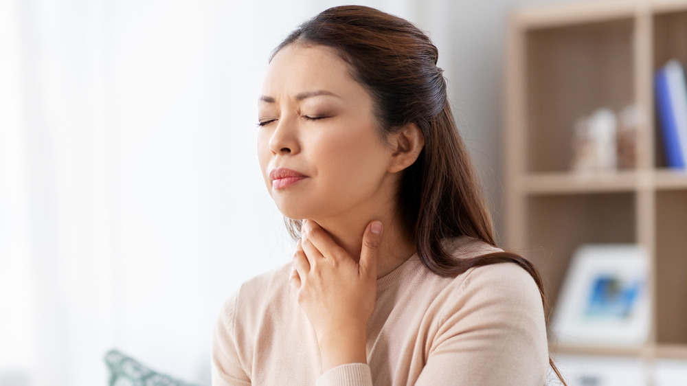 Woman holding her neck, sore throat