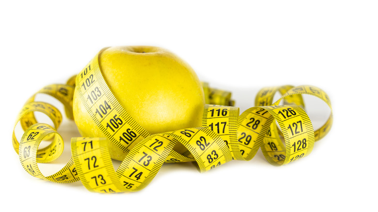 Yellow apple surrounded by measuring tape