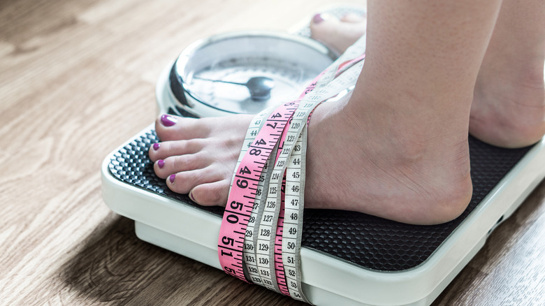 Feet on scale surrounded by measuring tape