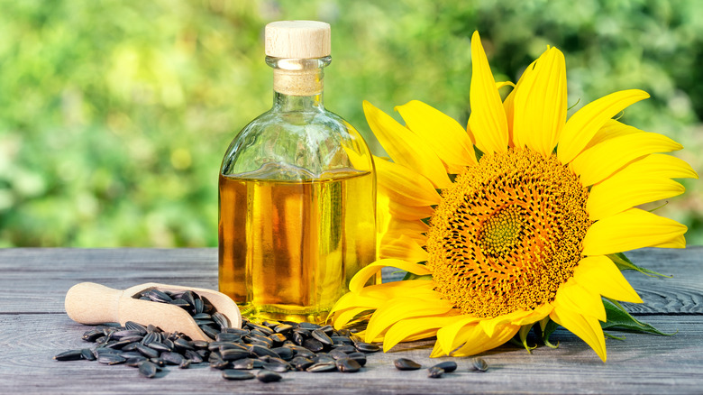 Bottle of sunflower oil next to a sunflower