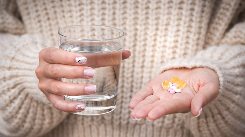 Woman taking vitamin supplements with a glass of water
