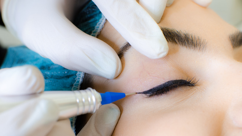 Close up of woman receiving permanent eyelid makeup tattoo