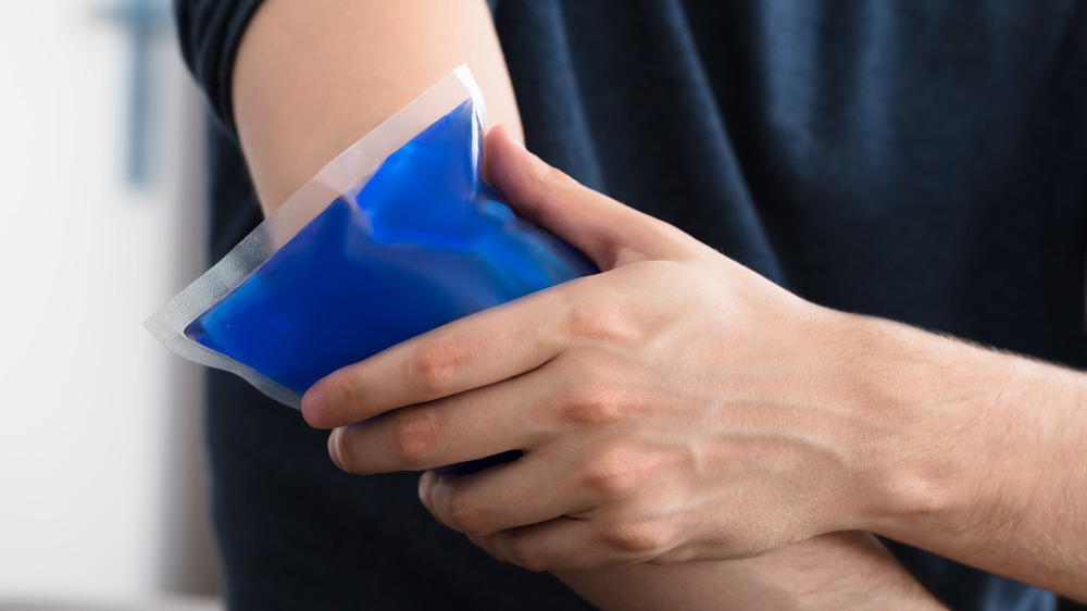 Person holding a blue gel ice pack up to their elbow