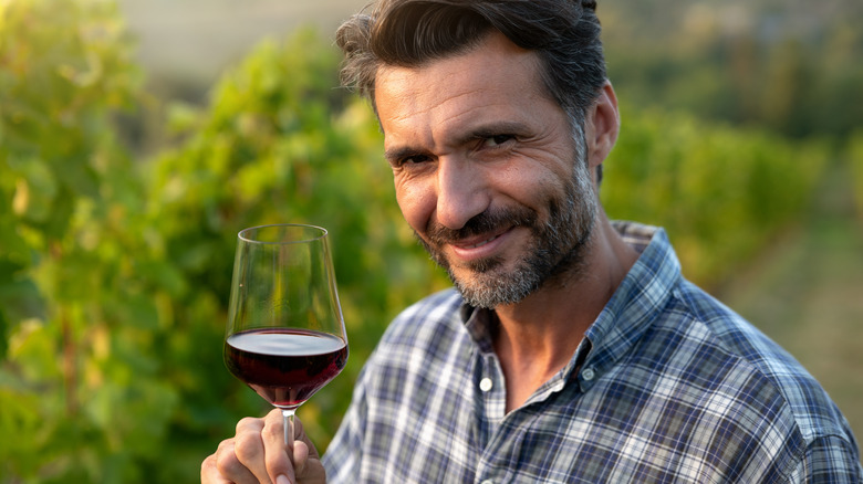 man holding red wine glass