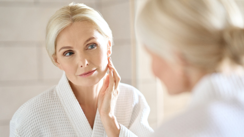 A woman looks at her face in the mirror