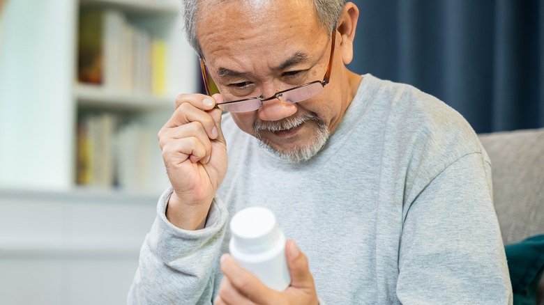 Man reading pill bottle instructions