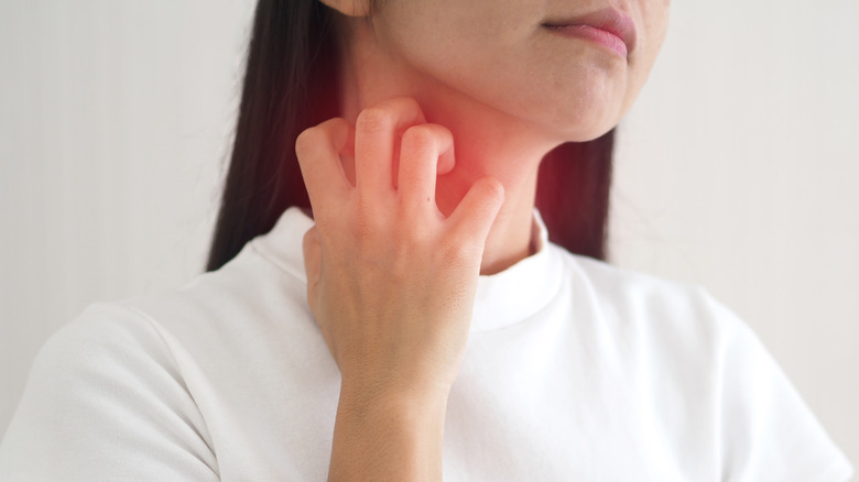 Person wearing T-shirt itching neck