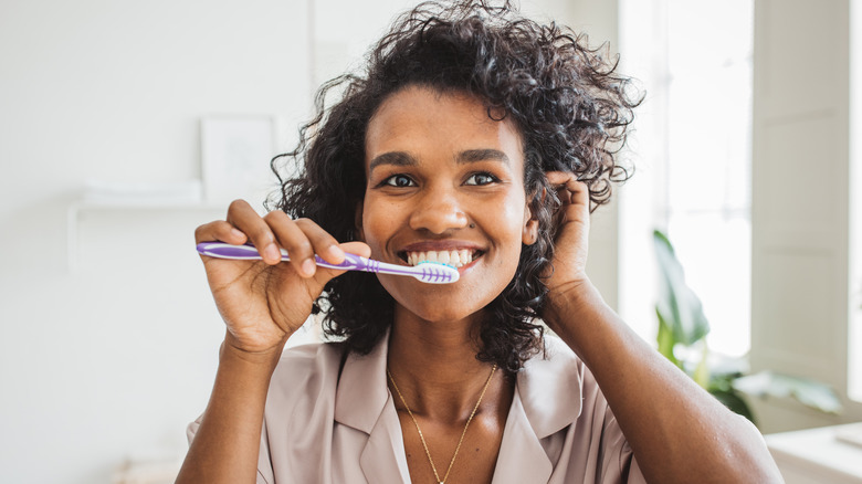 woman brushing her teeth in the mirror