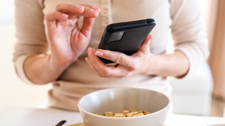 Hands taking smartphone picture of bowl of oats
