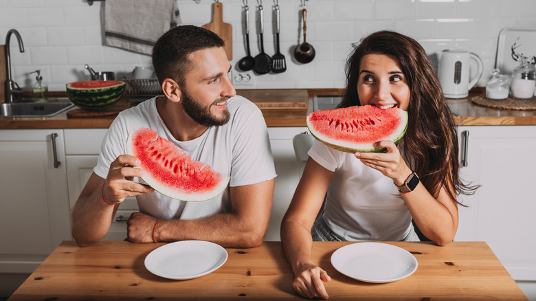 Couple eats watermelon in kitchen