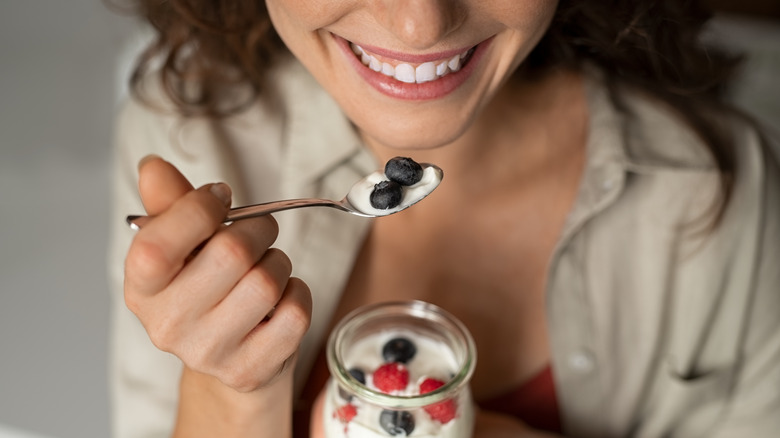 woman eating cup of yogurt