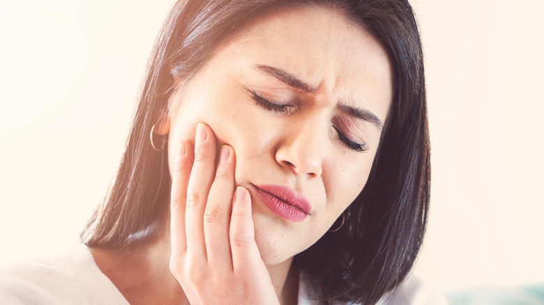 Woman holding her cheek and lower jaw in pain