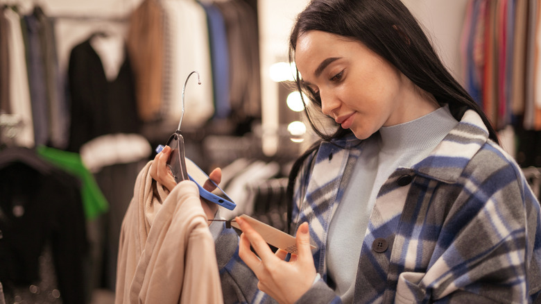 A woman looking at a clothing label in a store