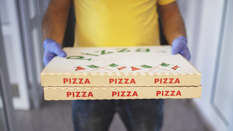 A man's hands holding boxes of pizza