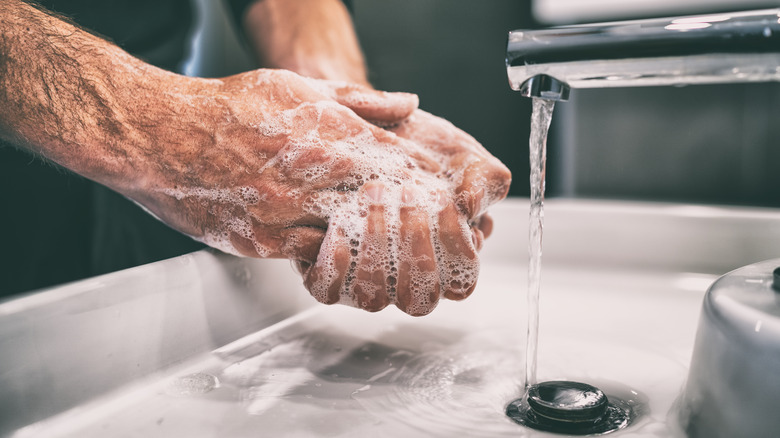 close up of a man scrubbing his hands with soap
