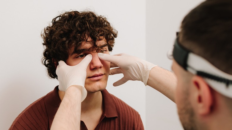 A medical professional examining a man's sinuses