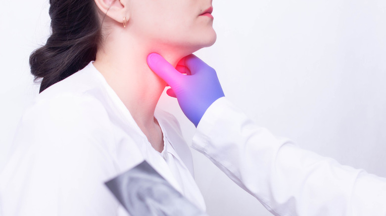 A doctor holding the front of a patient's throat