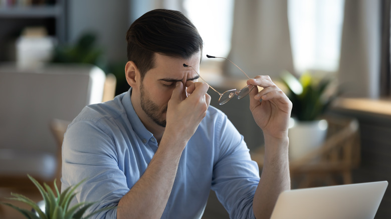 man sitting at desk holding glasses