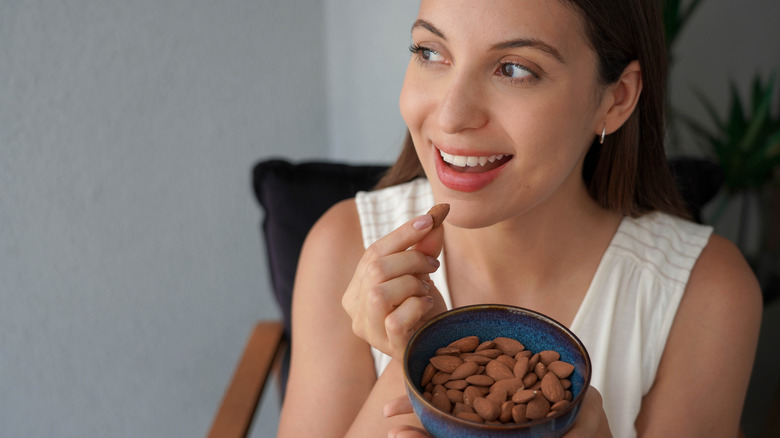 A woman eating almonds from a small bowl